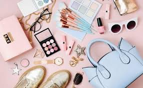 Stylish assortment of WOMEN ACCESSORIES, including handbags, sunglasses, and beauty products on a pink background.